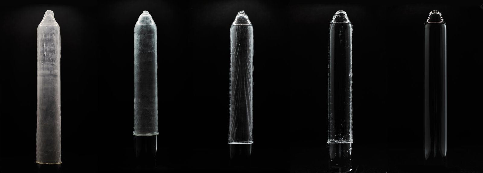 Five glass mandrels showing latex, polyisoprene and styreneisoprene condoms beside the Eudaemon hydrogel condom and a bare mandrel